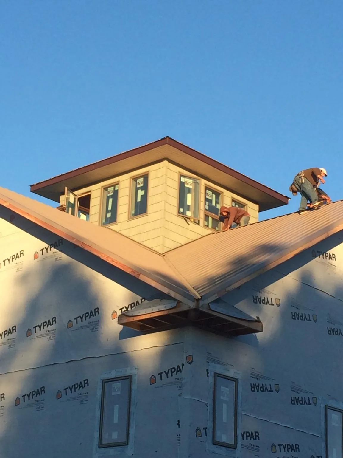 Roofers working around a rooftop cupola on a new metal roof at sunset — Roof Waterproofing in Midway by Roofing Brothers